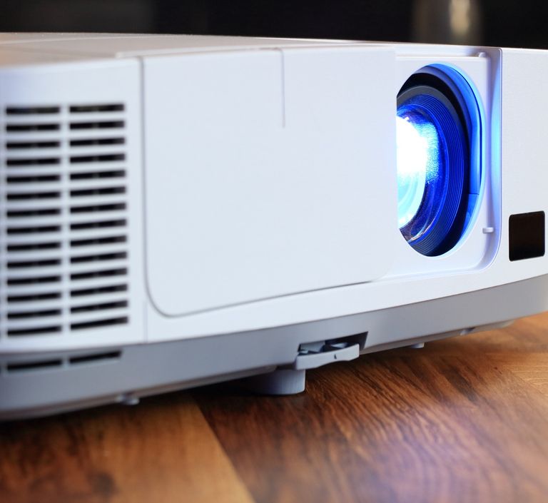 Close-up photo of an NEC projector with the lamp on.